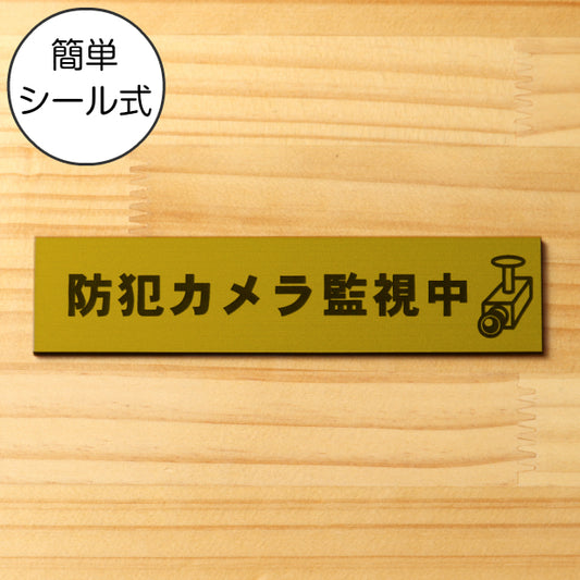 サインプレート (防犯カメラ監視中 マーク付) ゴールド 真鍮風 ステッカー プレート おしゃれ ドア ドアプレート 注意表示板 表示サイン 防犯 ダミー 小型 家庭用 セキュリティ 表札 門柱 標識 注意書き 庭 屋外OK シール式 金 アクリル製 日本製 (配送2)